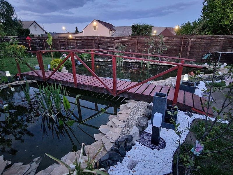 Kerti tó esti világítással és fahíddal